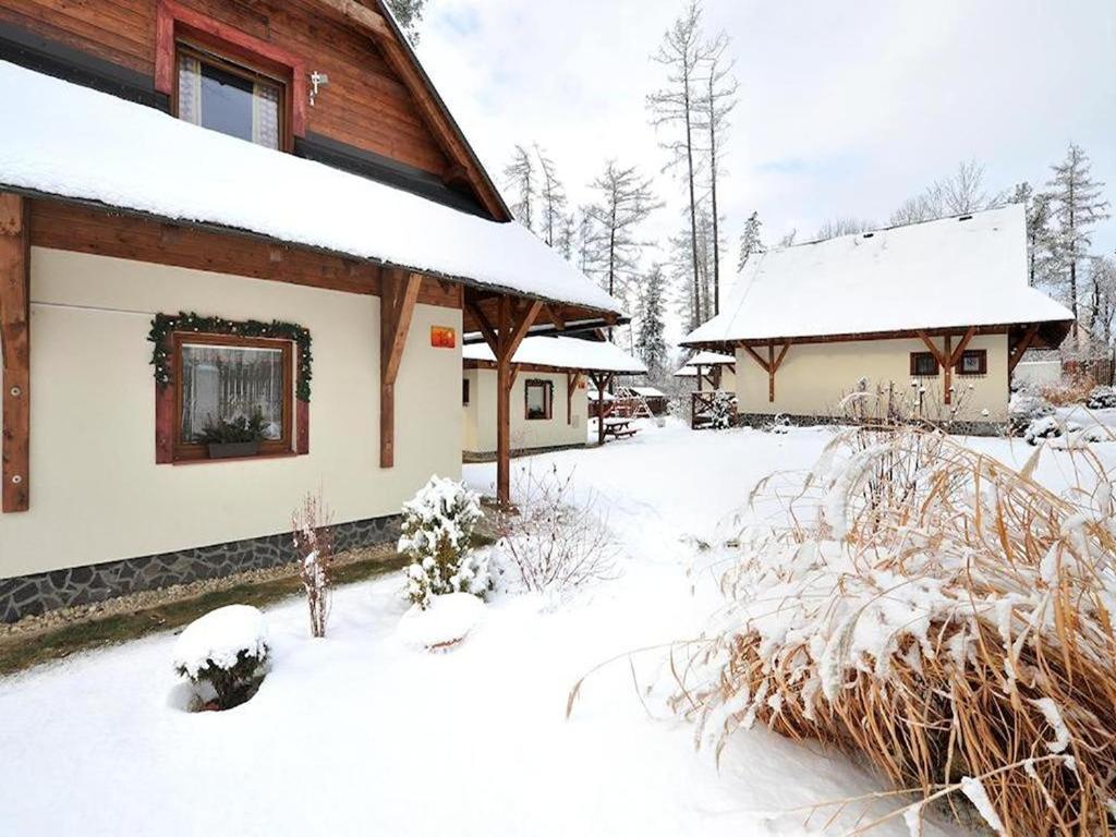 a house covered in snow next to a building at Chalúpka Bratov v resorte APLEND in Veľký Slavkov