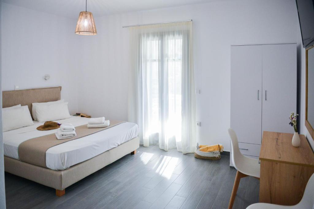 a white bedroom with a bed and a table and a chair at Agros Estate in Plaka