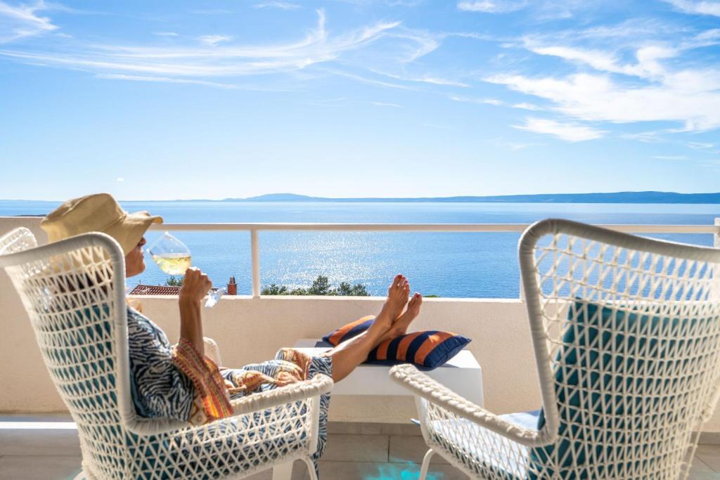 a man sitting in a chair with a glass of wine at Libera Apartments in Stara Baška