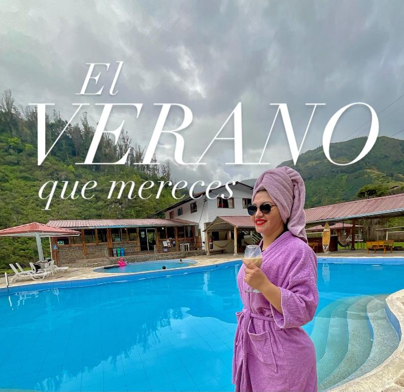 a woman in a purple robe standing in front of a pool at Playita Salomon in Baños
