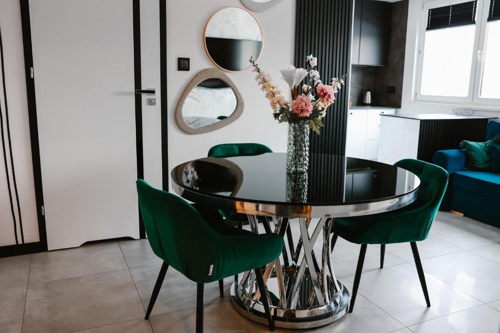 a dining room with a glass table and green chairs at Apartament Patka Wysoki STANDARD in Grudziądz