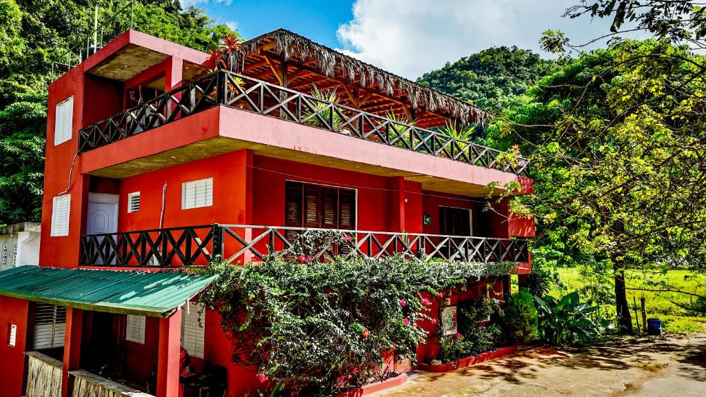 a red building with a balcony on the side of it at Hostal Luz Del Valle in Santa Bárbara de Samaná
