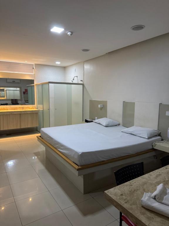 a bedroom with a large bed and a kitchen at Motel Canadá moto gp in Senador Canedo