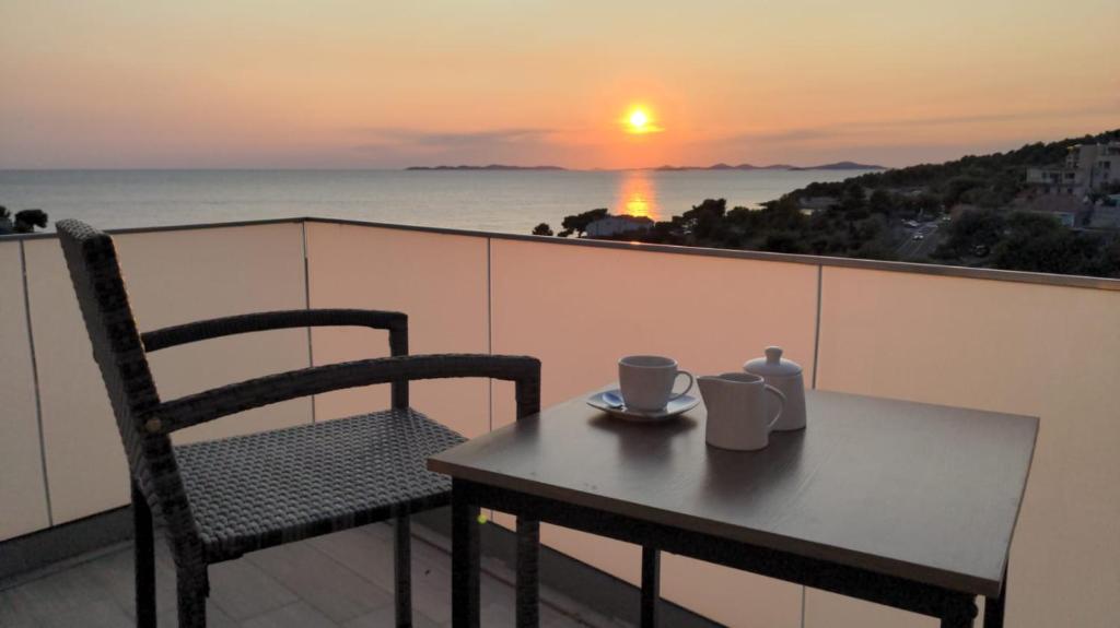a table and a chair on a balcony with a sunset at Sunset Bay Casa in Dolac