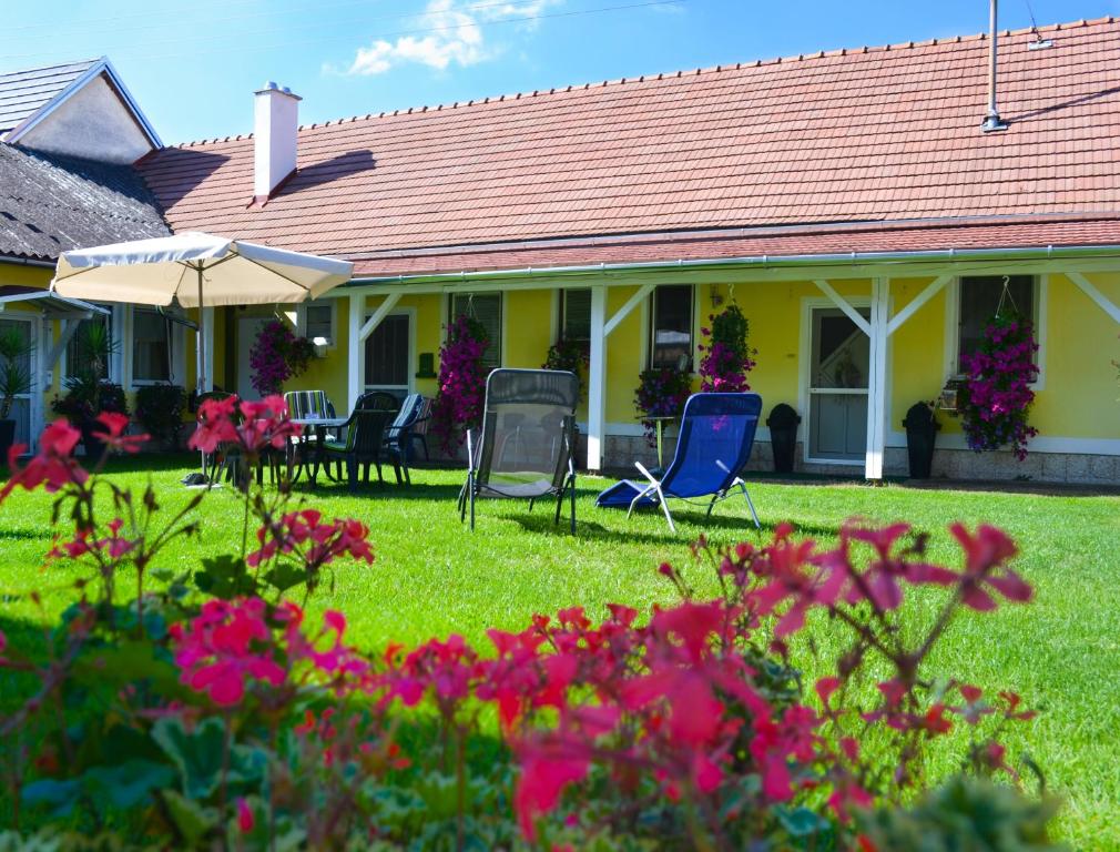 une maison avec des chaises, un parasol et des fleurs dans l'établissement Ferienwohnung Gerersdorf, à Gerersdorf bei Güssing
