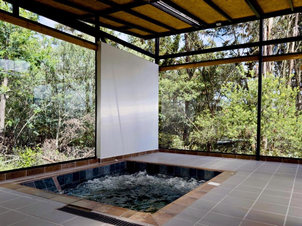 a hot tub in a room with large windows at Ziatá in Simijaca
