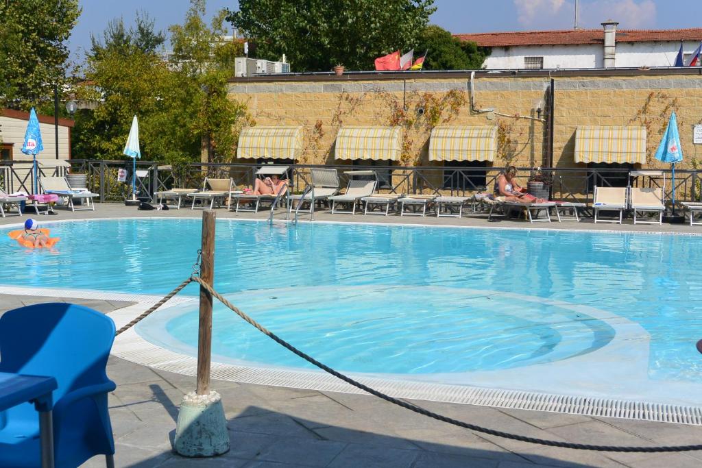 a large blue swimming pool with people sitting in chairs at Camping Village Torre Pendente in Pisa