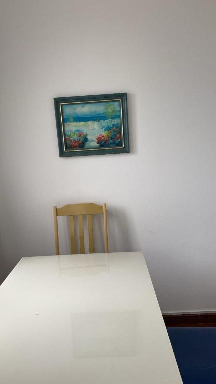 a white table with a chair and a painting on the wall at Apartamento central próximo à catedral com 2 quartos e 2 banheiros in Santo Ângelo