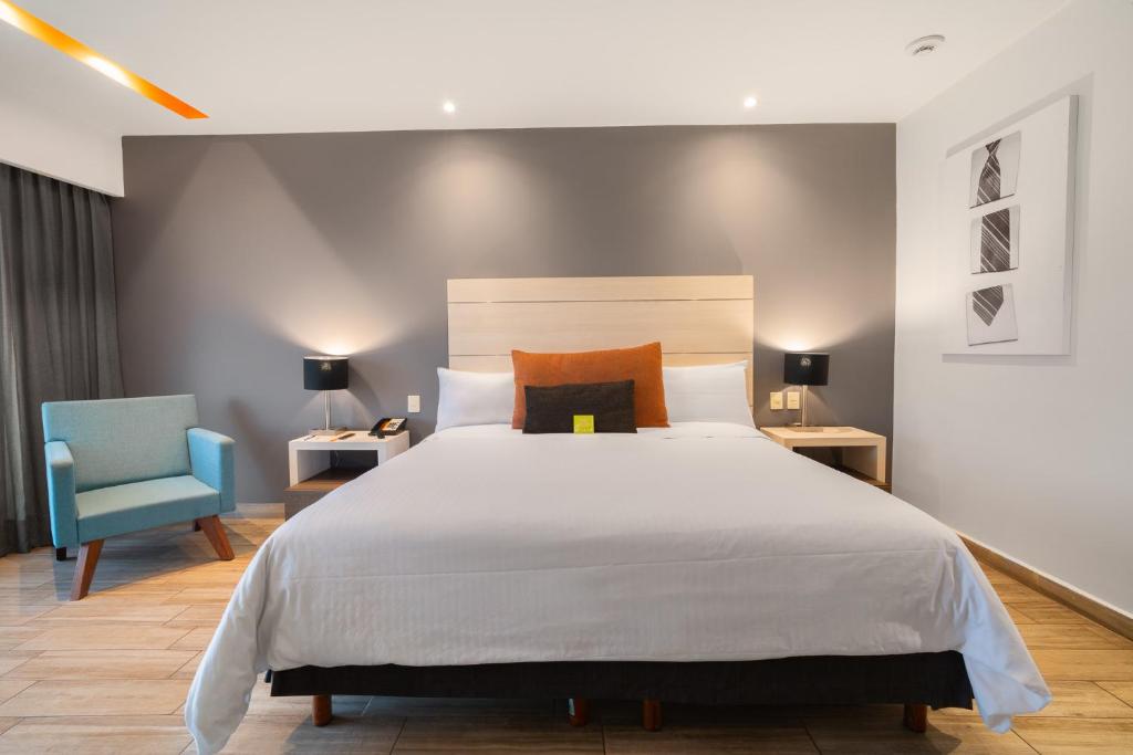 een slaapkamer met een groot bed en een blauwe stoel bij Real Inn Perinorte in Mexico-Stad