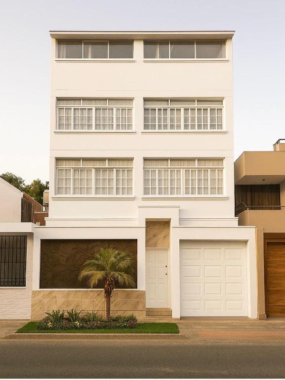 a white house with two garage doors and a palm tree at Huacachina Boutique Hotel in Ica