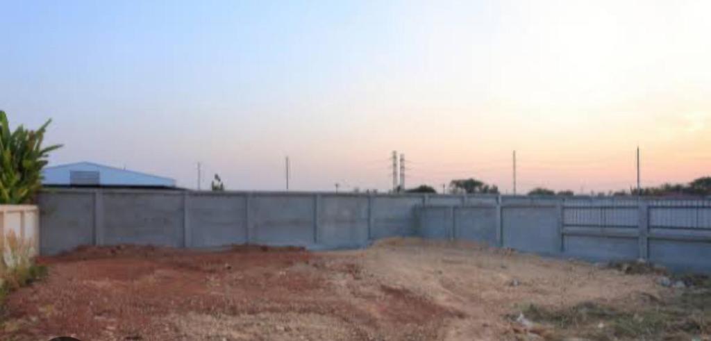 a fence in front of a building with a field at Terreno in São Pedro da Aldeia
