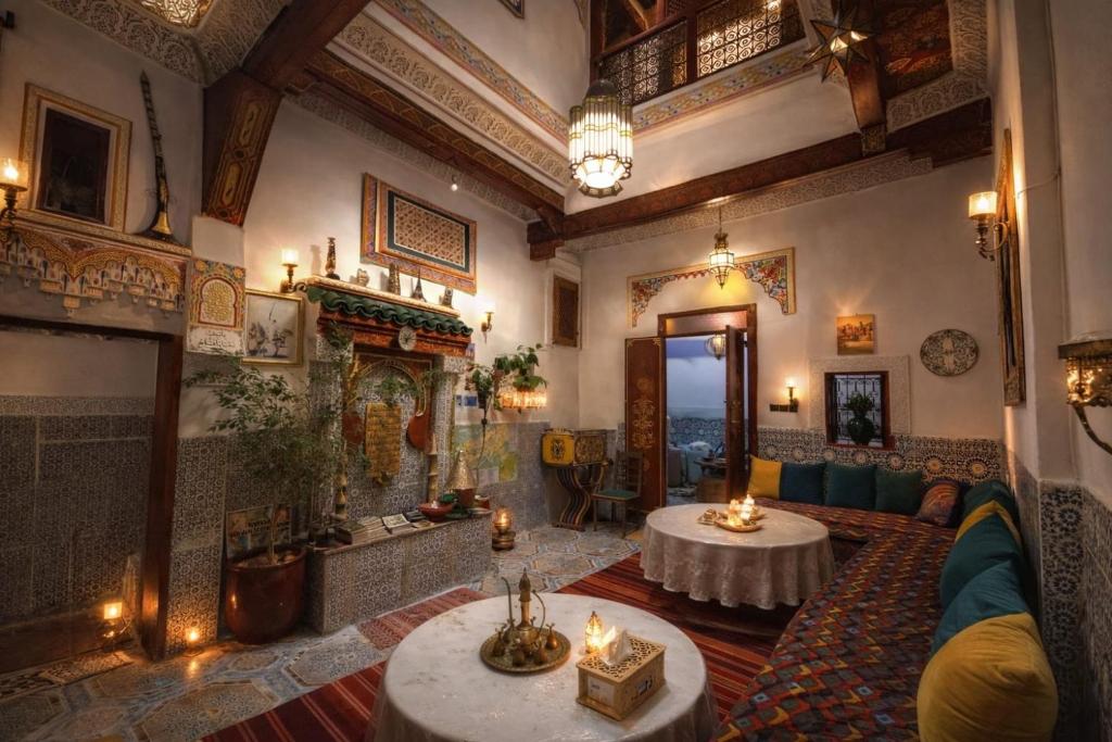 a living room with two tables and a fireplace at Dar Enouiina in Fez