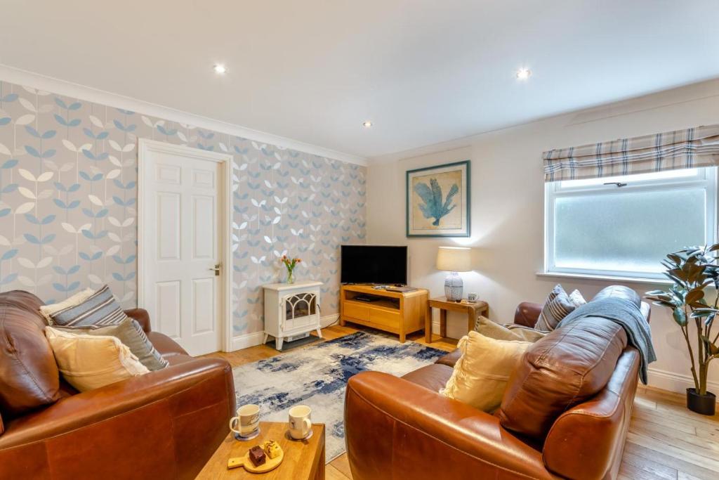 a living room with two leather couches and a television at 2 Bed in Bamburgh oc-gd1273 in Bamburgh