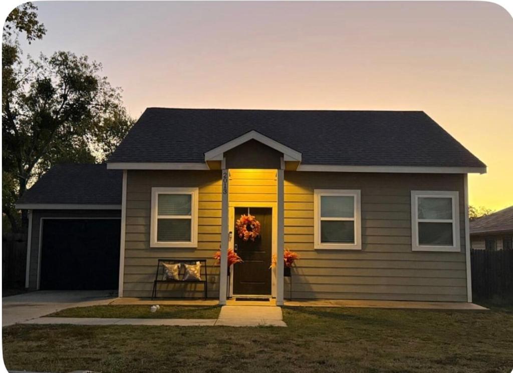 a yellow house with a wreath on the door at Beautiful modern 3 bed 2 bath in Fort Worth