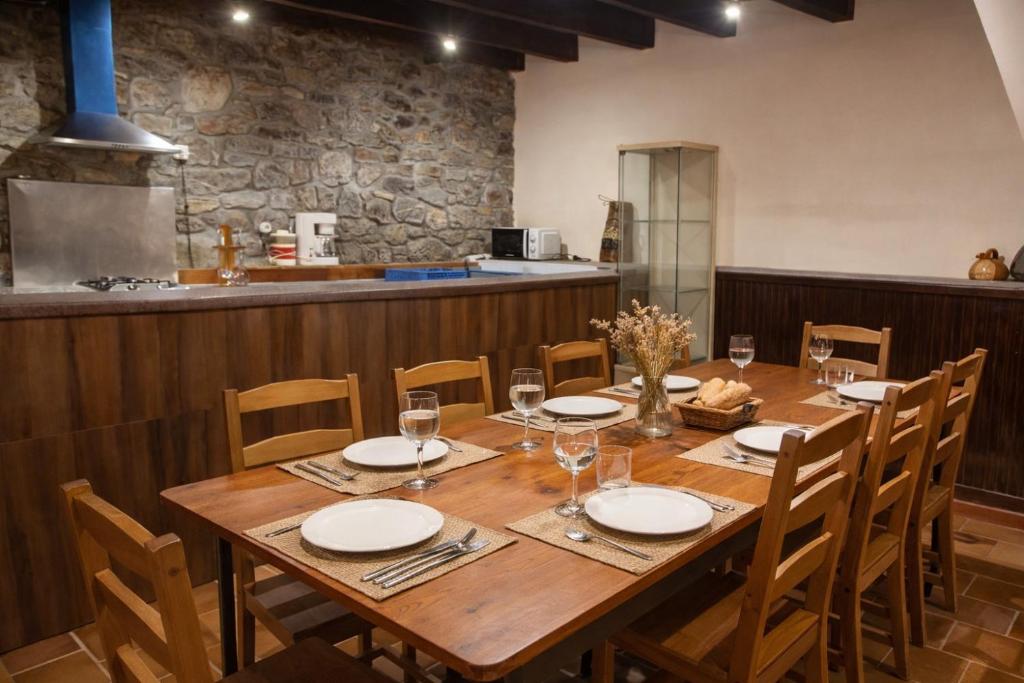 a large wooden table with chairs and a kitchen at Casa La Farrapona Torrestío Babia in Torrestío