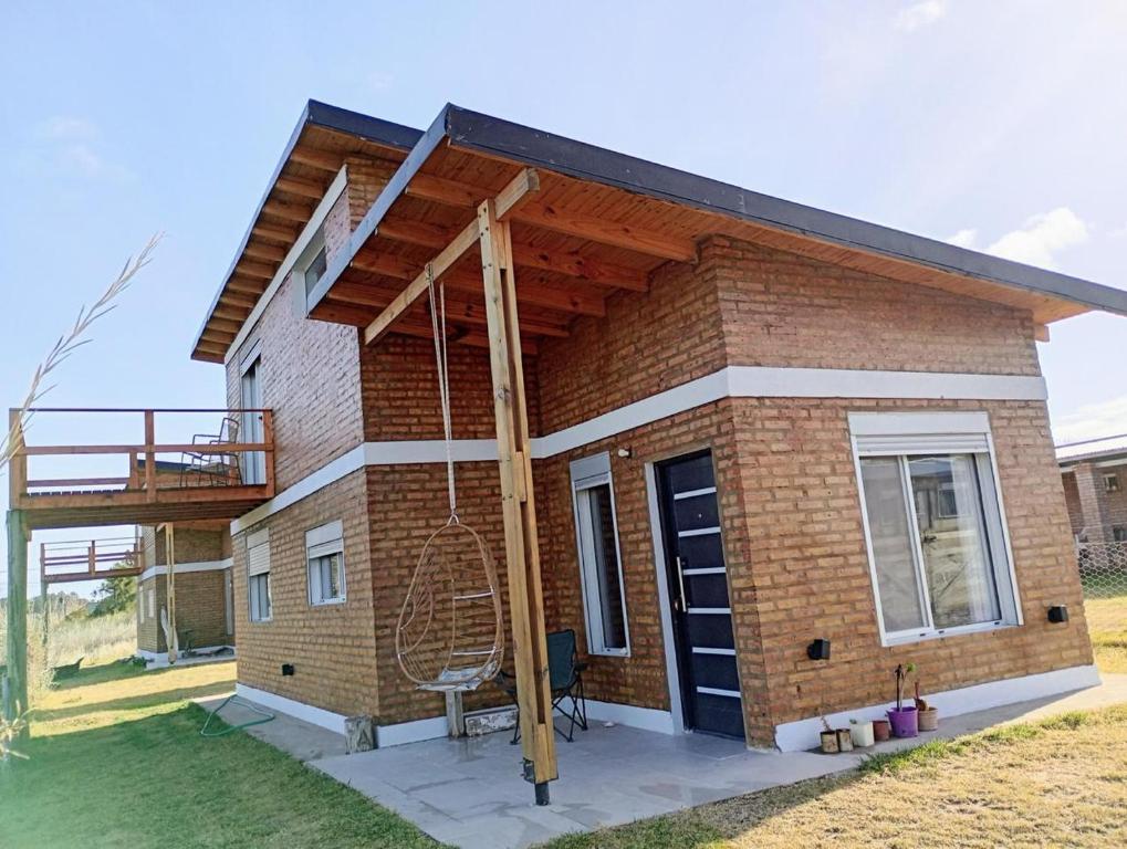a small brick house with a porch and a balcony at Village Pehuen in Balneario Pehuén-Có