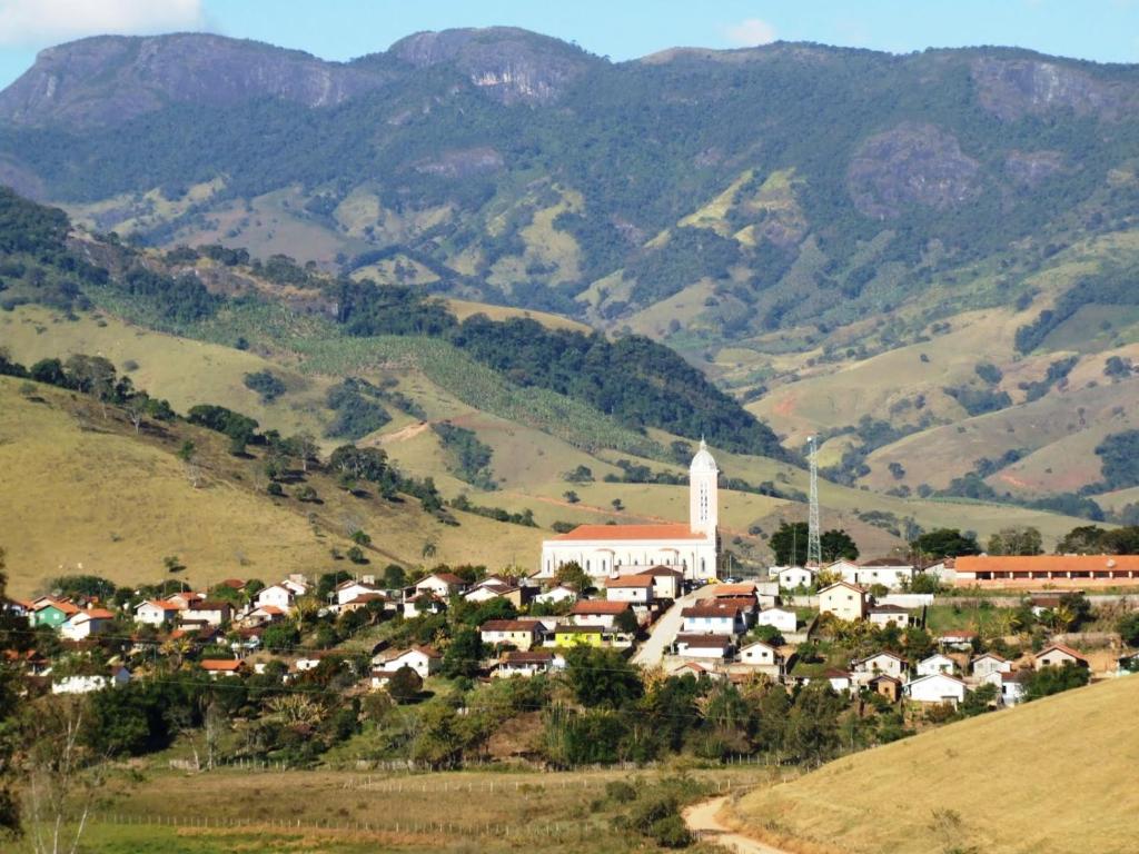a small village with a church and mountains in the background at Rancho Ca Fé - Casa Rural in Brazópolis