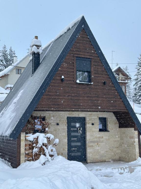 a barn with a snow covered roof and a window at Vila Ramonda in Žabljak