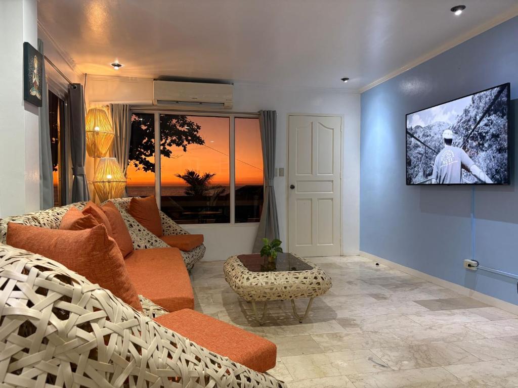 a living room with a couch and a tv on a wall at Bobby's Villa Beachfront, Paringao, La Union in Bauang