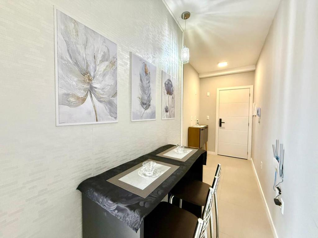 a dining room with a table and some pictures on the wall at Apartamento Pousada Essence Navegantes Praia Gravata in Navegantes