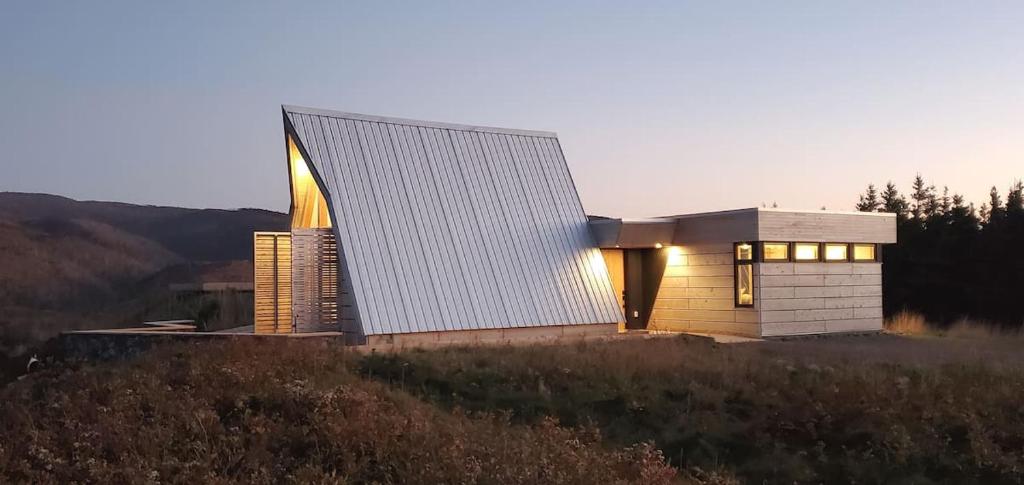 a house with a lit up facade on a hill at Cedar Peak - Design-Forward Barrier-Free Chalet in Grand-Etang