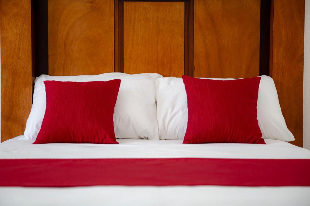 a bed with red and white pillows on it at Hotel alcazar de luna in Chilpancingo de los Bravos