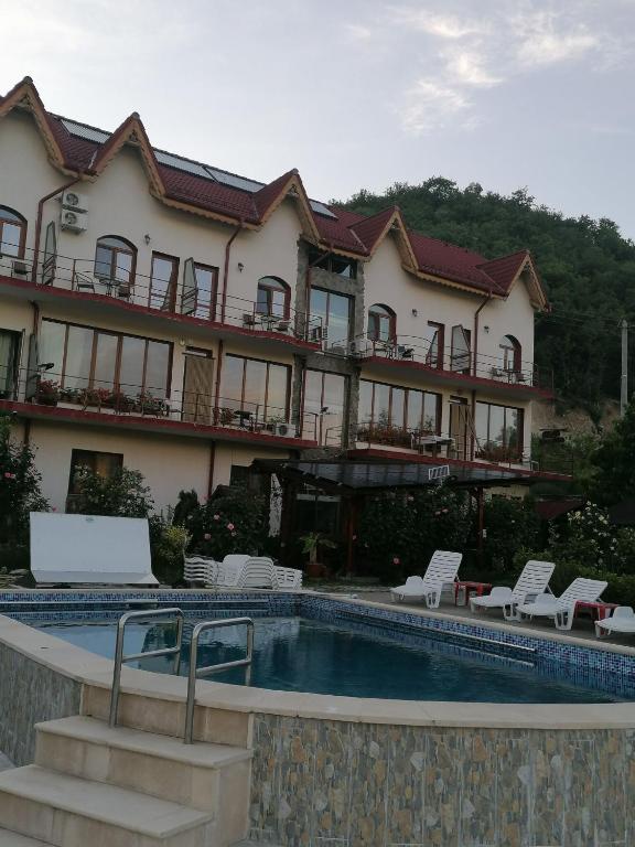a hotel with a swimming pool in front of a building at Cabana Delfinul - Cazanele Dunarii in (( Plavişeviţa ))