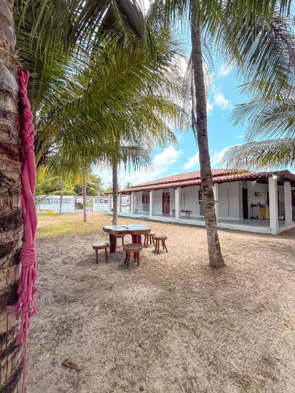 a picnic table in front of a building with palm trees at Casa Mar e Rio Milagres in São Miguel dos Milagres
