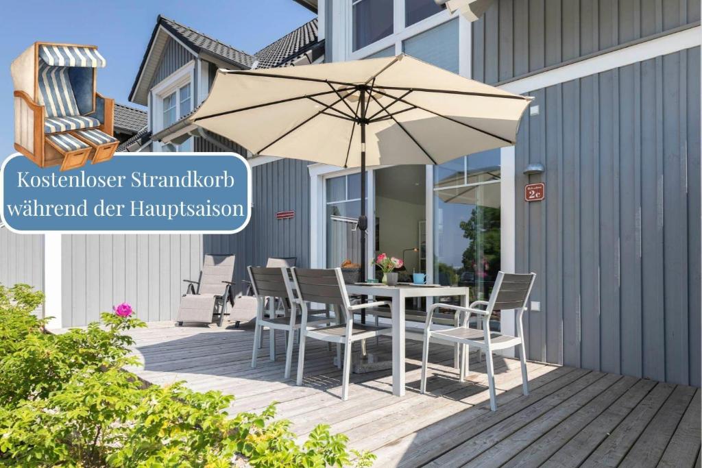 a table and chairs with an umbrella on a deck at Ferienhaus-Belvedere-2-c in Blekendorf