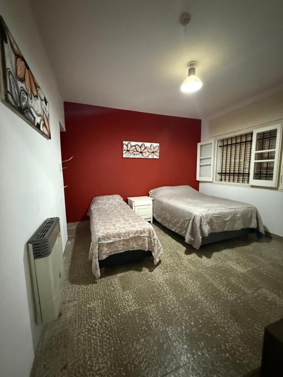 a bedroom with two beds and a red wall at HOSTEL del MUNDO in Villa María