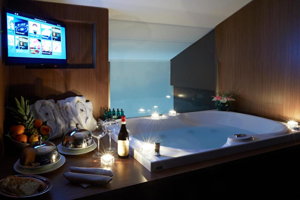a bath tub with a bottle of wine and a television at Hotel The Building in Rome