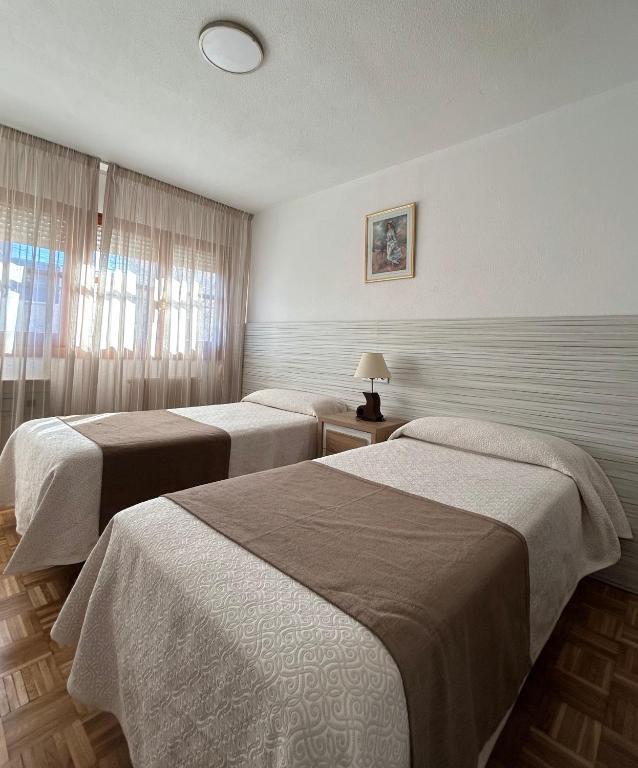 ein Hotelzimmer mit zwei Betten und einem Fenster in der Unterkunft Hotel Can-Vic in Guadalajara