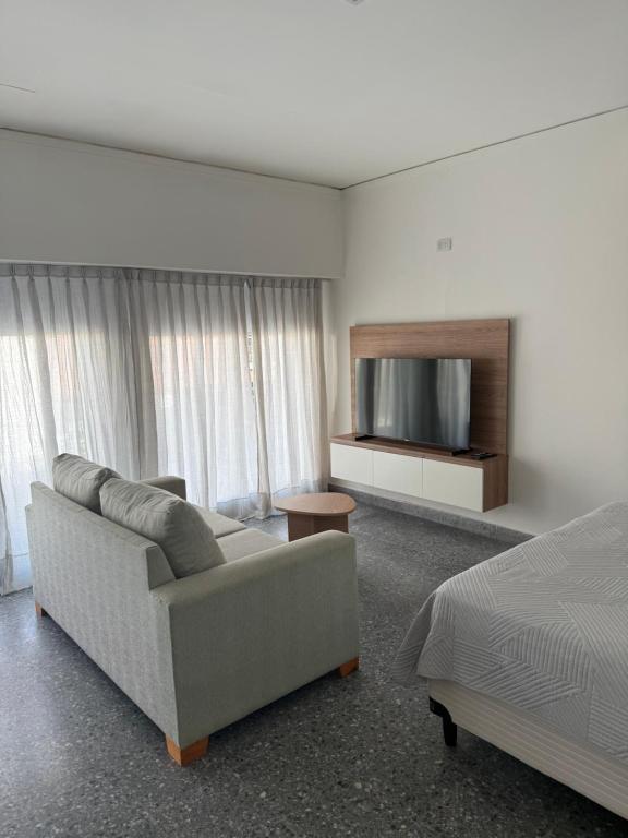 a living room with a couch and a flat screen tv at Studio Ikuma in Esperanza