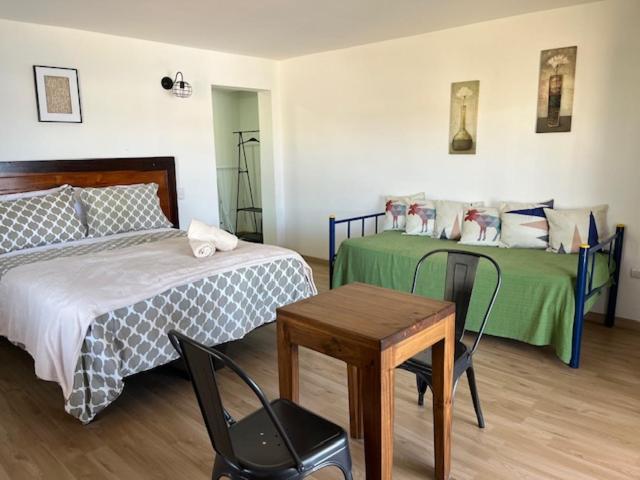 a bedroom with two beds and a table and a chair at Costanera240 in El Quisco