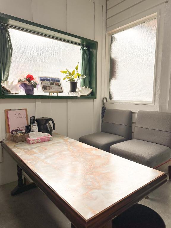 a room with a table and two chairs and a window at ゲストハウスまるとく in Yoron
