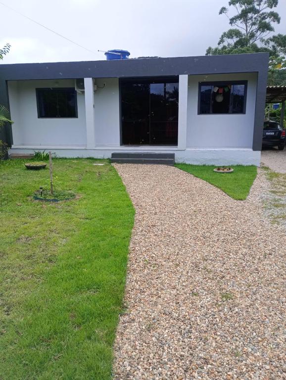 a white house with a gravel driveway at Aconchego da Montanha in Garopaba