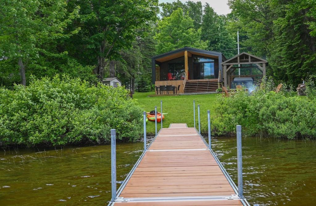 a wooden dock with a cabin on the side of a lake at Refuge du Kodiak BORD DE L EAU in Sainte-Germaine-du-Lac-Etchemin