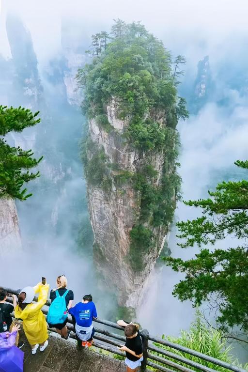a group of people sitting on a bench in front of a mountain at Zhangjiajie Southgate Flower Garden Lodge -5 Mins to Forest Park - Free Forest Park Shuttle - Travel Guide - Free Breakfast in Zhangjiajie