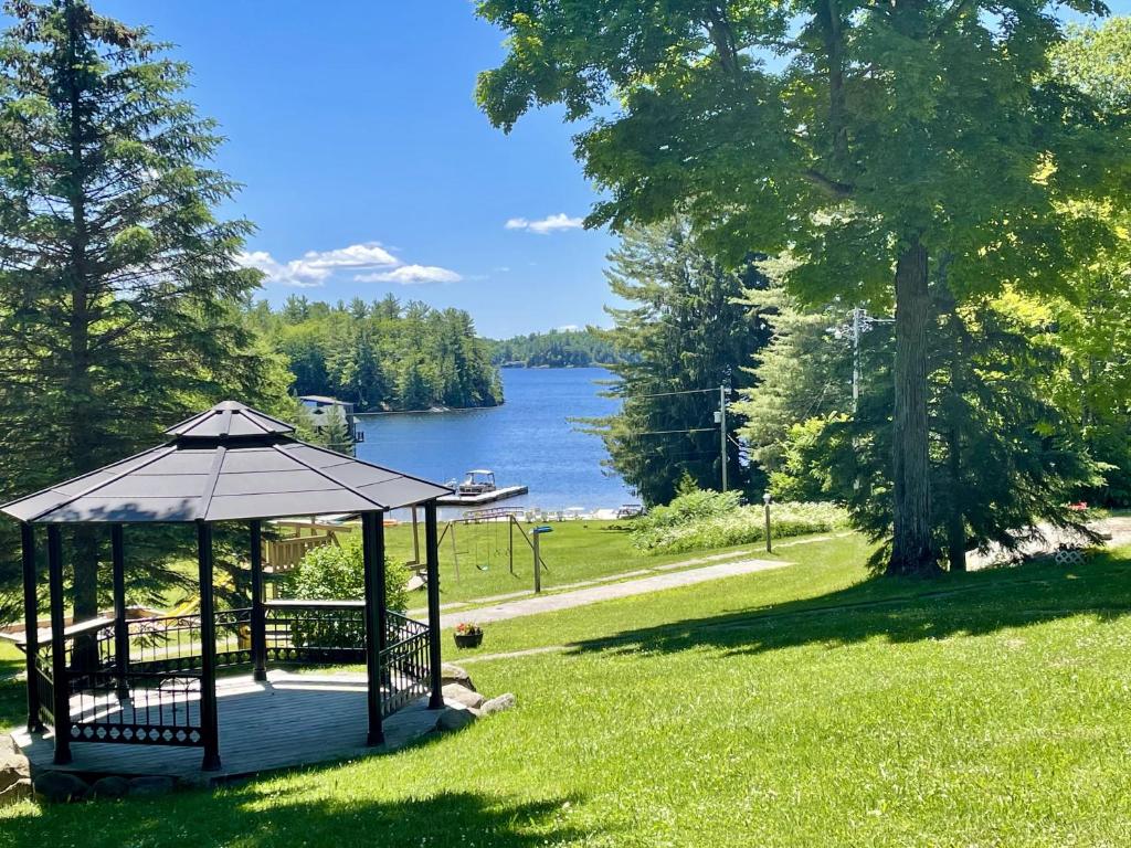 a gazebo in the grass next to a lake at Stunning Lakeview Muskoka Pier 100 Resort in Port Carling