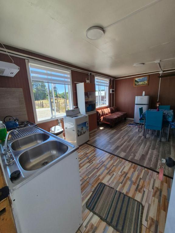 a kitchen with a sink and a living room at Cabaña ByB in Dalcahue