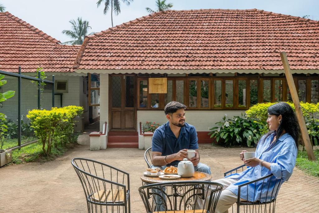 a man and woman sitting at a table in front of a house at The Anexure - Great Estate Stay for Remote Work in Siddapur