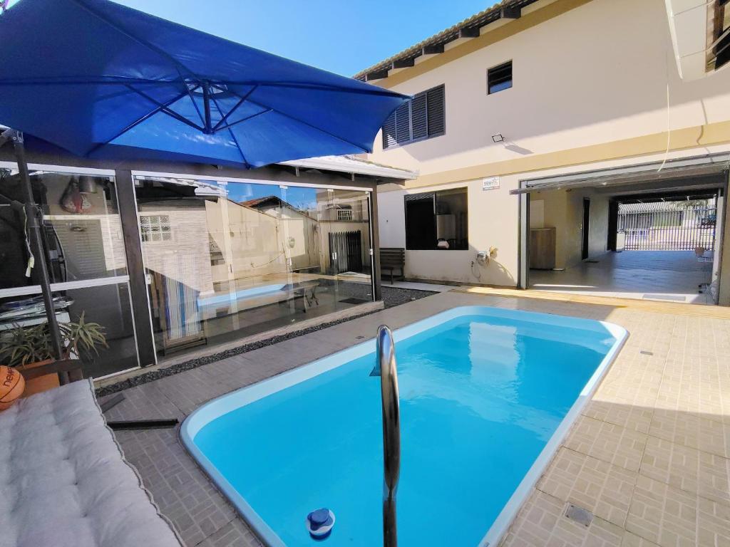 a large blue swimming pool with a large blue umbrella at Sobrado 4 quartos com piscina praia do tabuleiro in Barra Velha