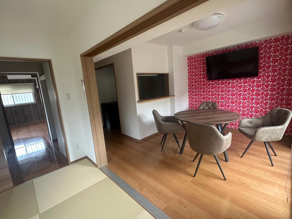 a room with a table and chairs and a red wall at ウエストワン サウス106Hanatebako in Hitoyoshi