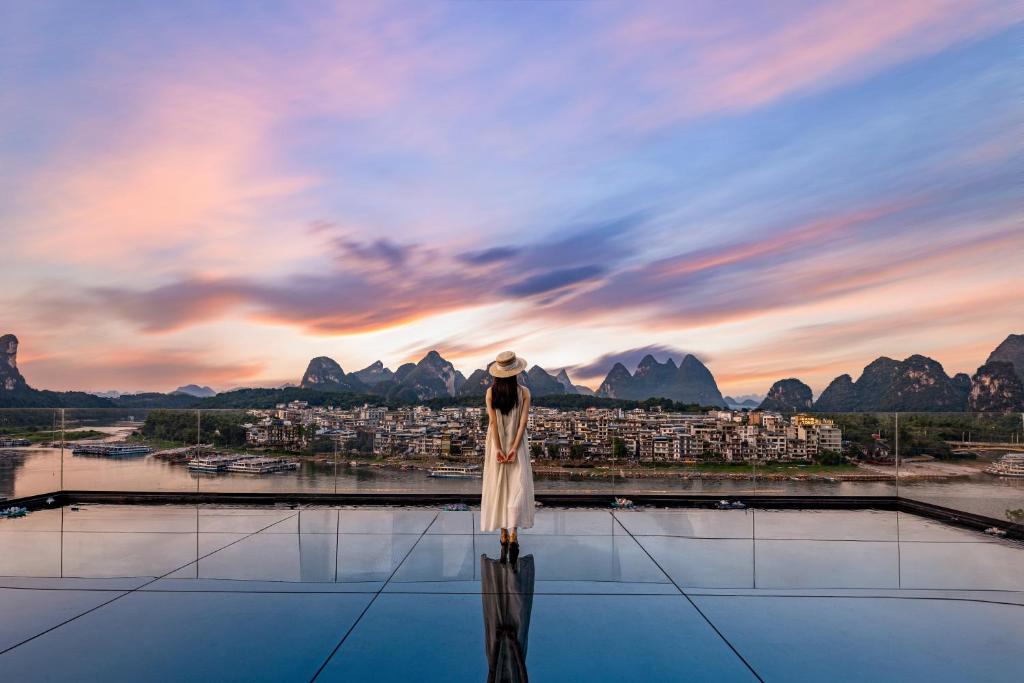 a woman standing on the roof of a building looking at a city at Guilin Yangshuo Shixi Landscape Hotel in Yangshuo