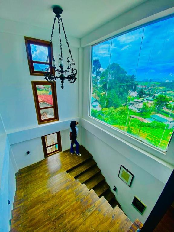 a person standing on a staircase looking out of a large window at The Budget White House Hotel in Nuwara Eliya