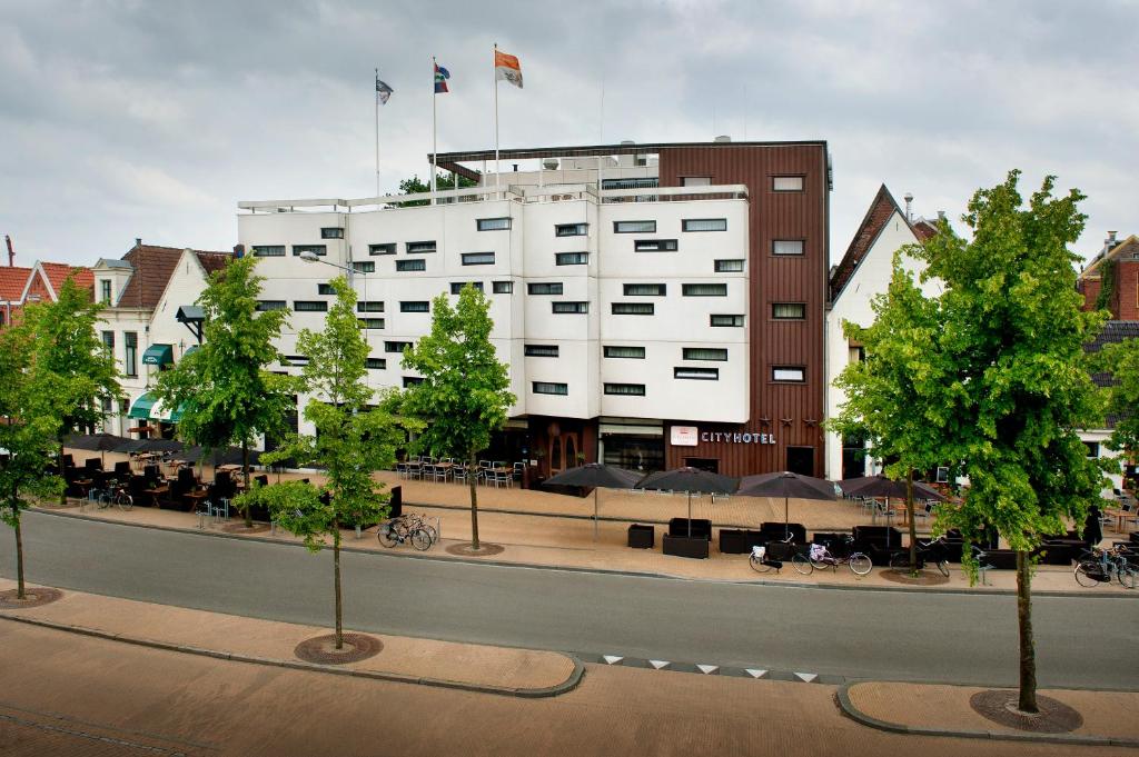 a large white building with two flags on top of it at City Hotel Groningen in Groningen