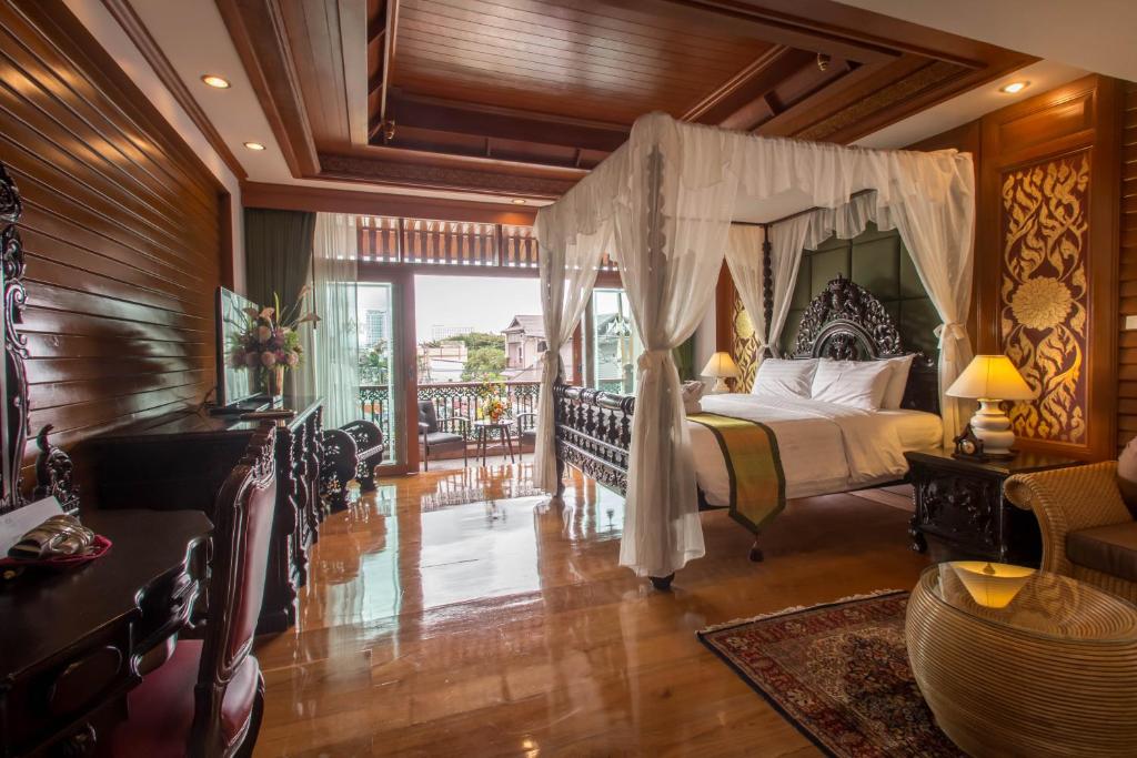 a bedroom with a canopy bed and a balcony at Villa Sirilanna Hotel in Chiang Mai