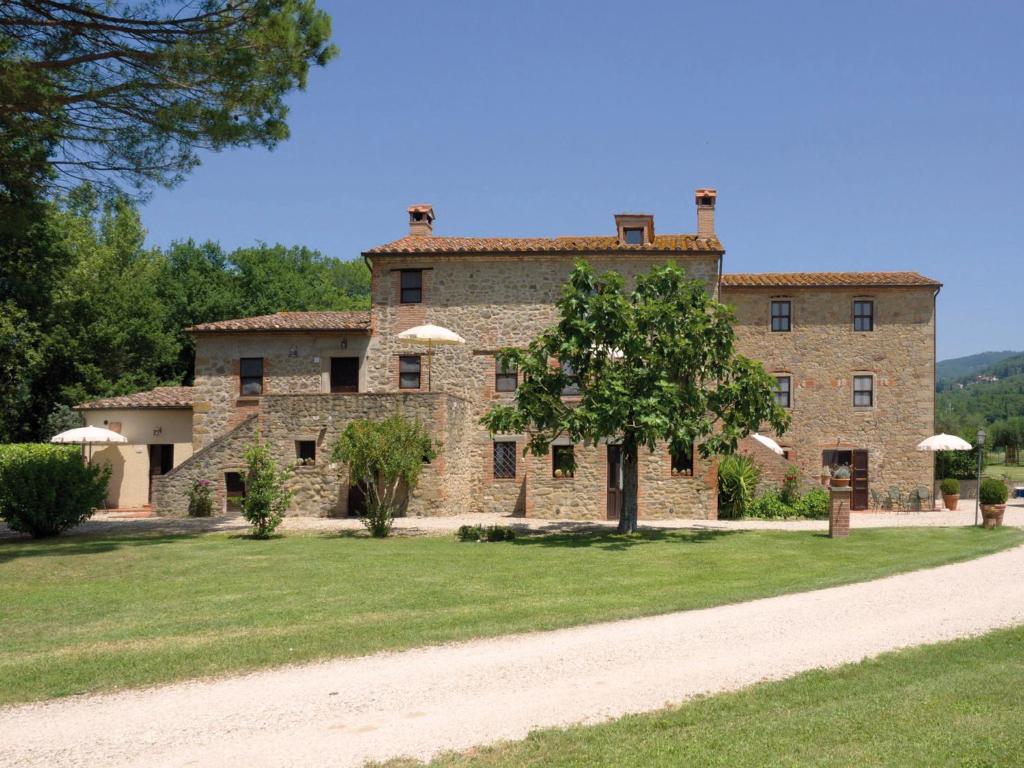 une vieille maison en pierre avec un arbre en face de celle-ci dans l'établissement Il Piratello - Agriturismo Baldeschi, à Tuoro sul Trasimeno