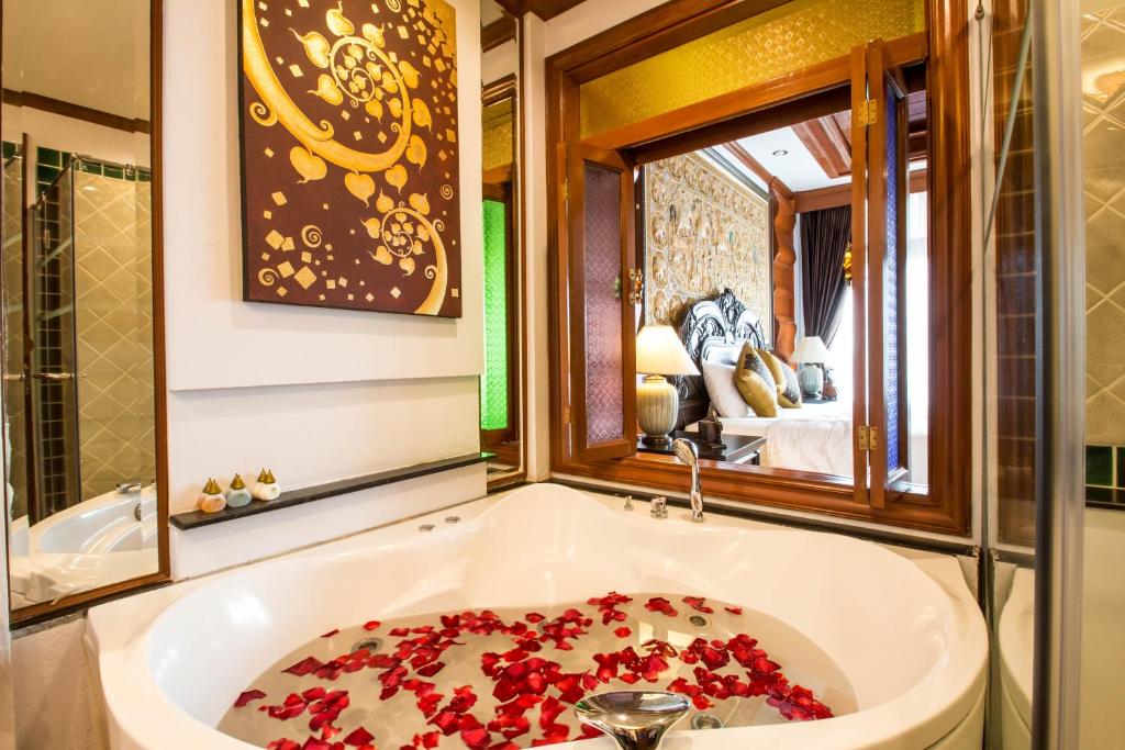 a bath tub filled with red flowers in a bathroom at Villa Sirilanna Hotel in Chiang Mai