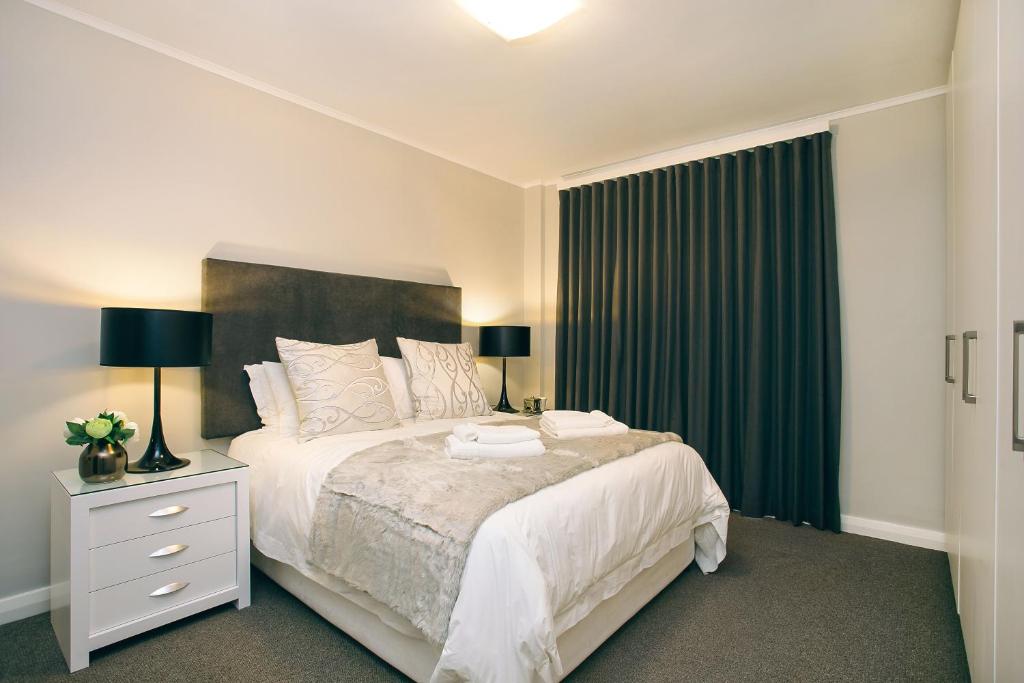 ein Schlafzimmer mit einem großen Bett mit einem grünen Vorhang in der Unterkunft Superior Apartment Mayfair in Kapstadt